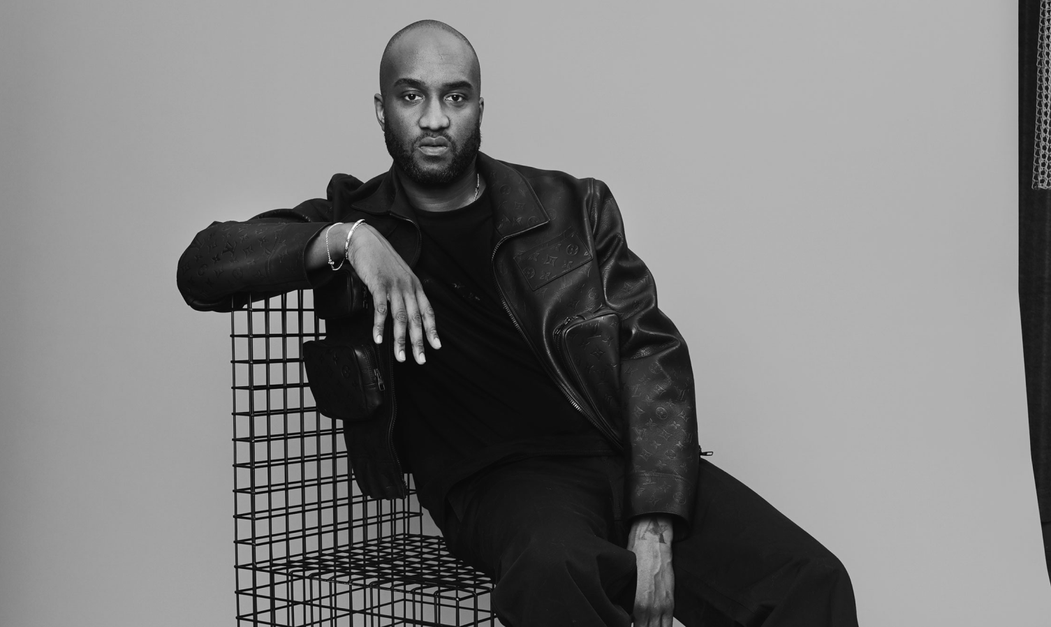 A portrait of Virgil Abloh sitting in a wireframe chair